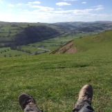 feet in forefront of green hills